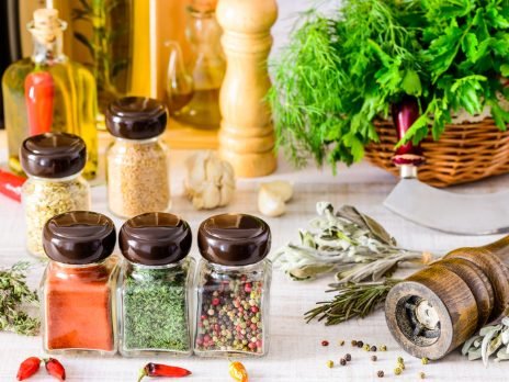 Sazonadores y especias en frascos, junto a hierbas frescas